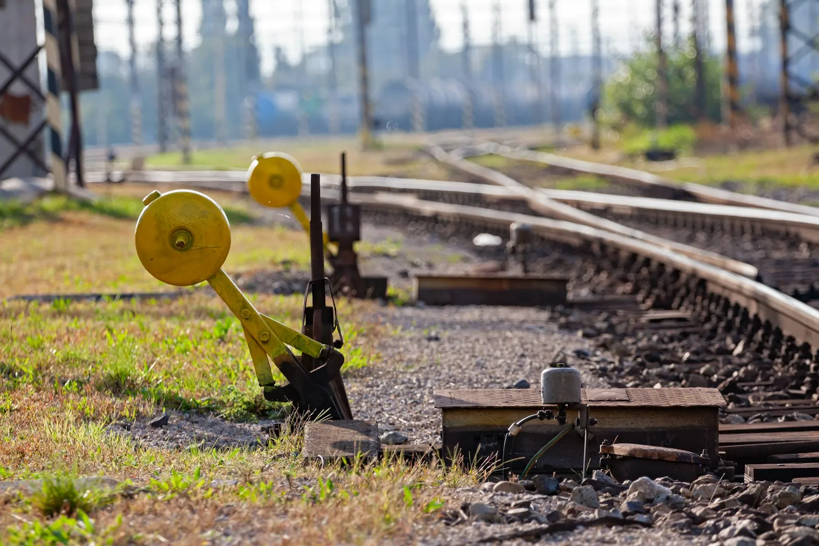 Yellow manual track switch levers on a rail siding in daylight