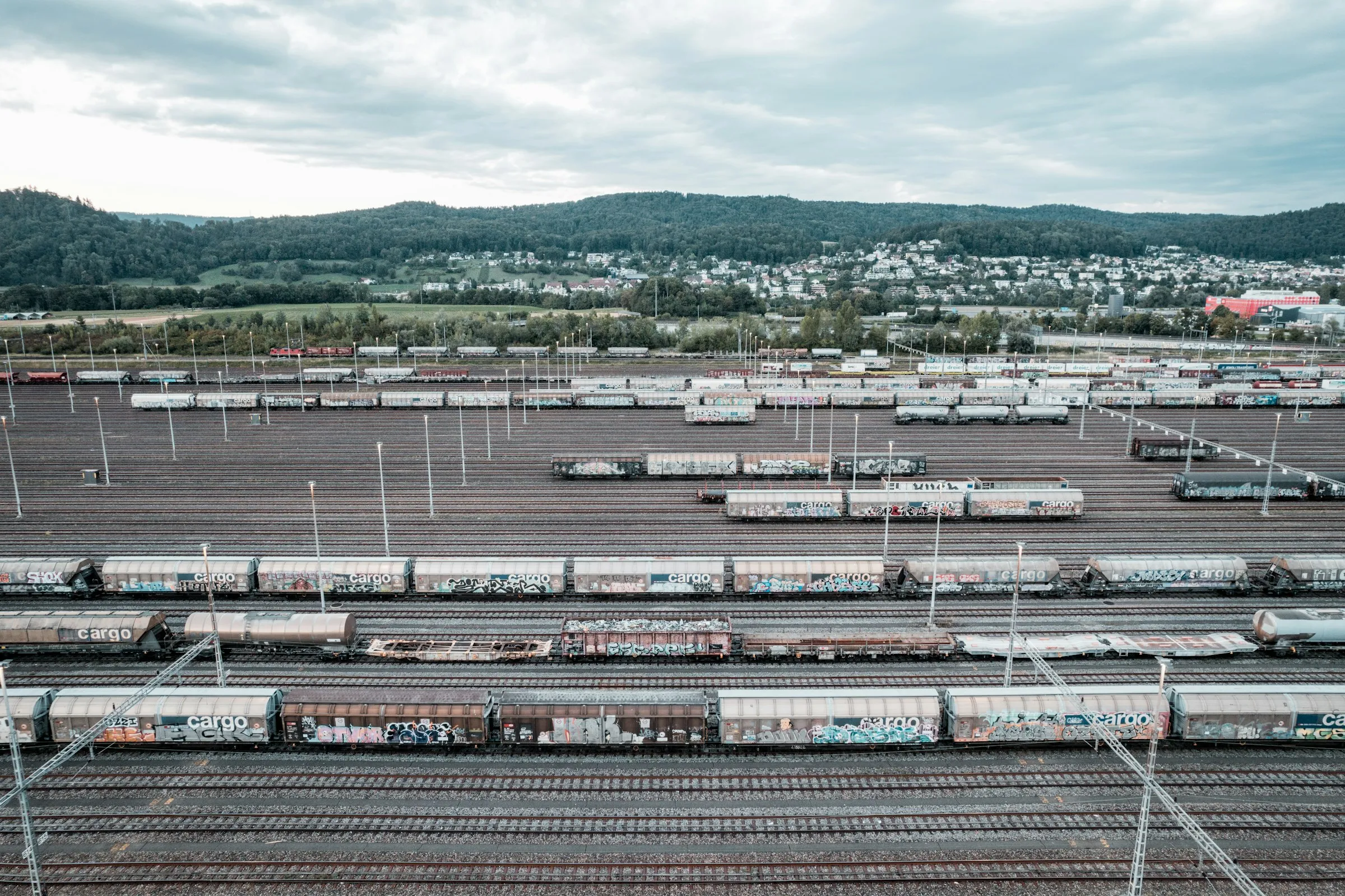 A wide rail yard filled with freight cars under an overcast sky
